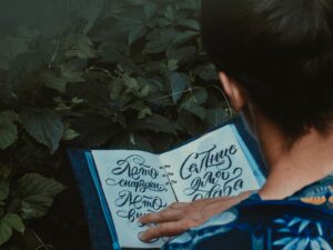 person in blue and white floral shirt reading a book